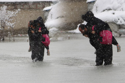Evinin önünde biriken su nedeniyle çocuklarını sırtında taşıyor